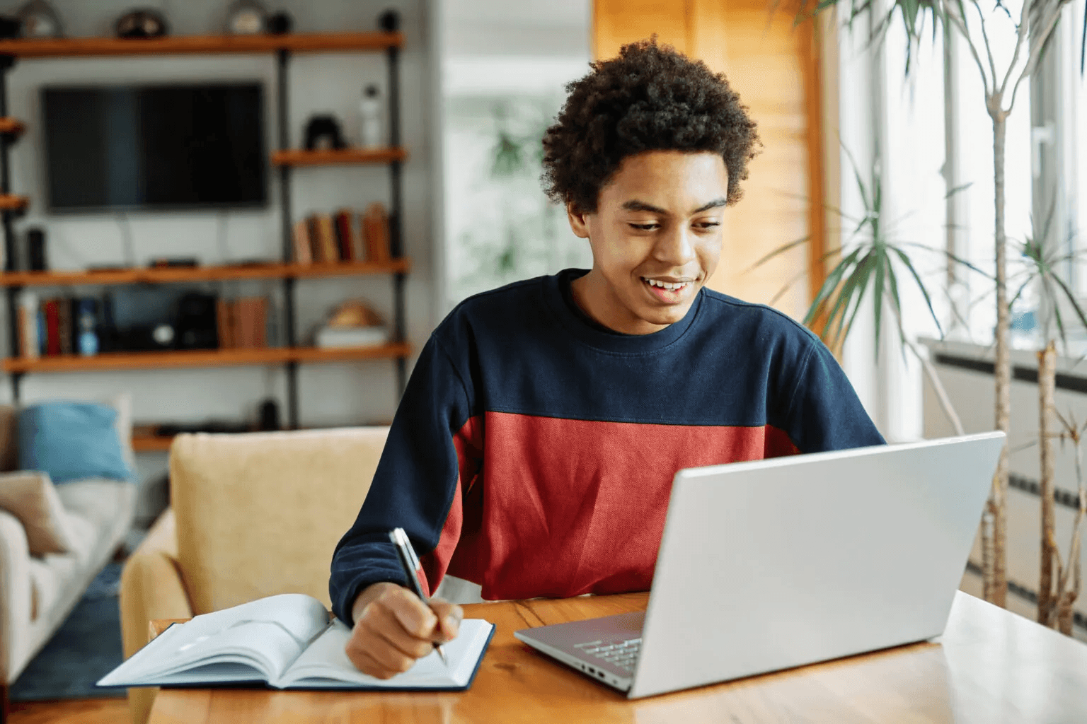Student writing notes with laptop