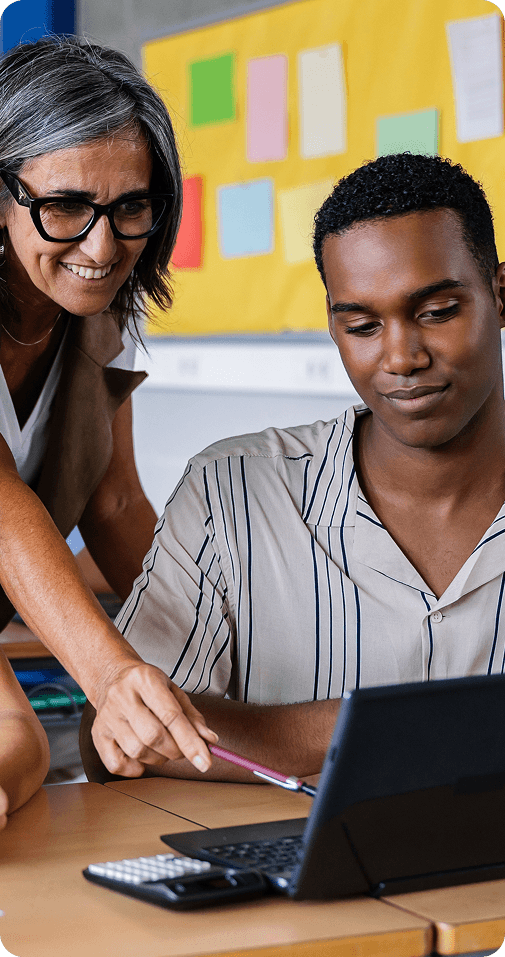 Female mentor guiding young educator at a laptop